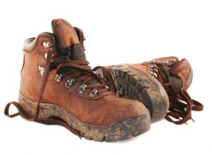 A pair of muddy brown hiking boots, isolated on white.